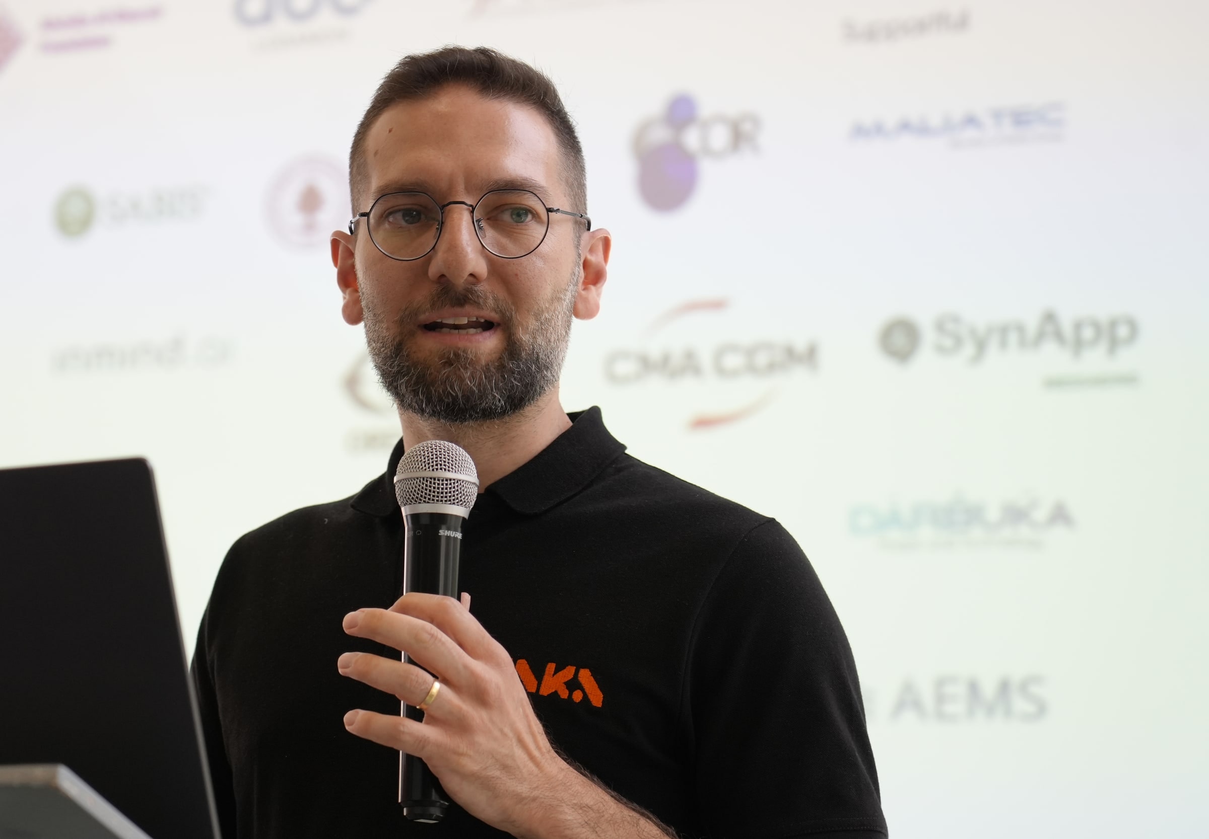 Christophe Zoghbi, CEO of ZAKA, speaking into a microphone on stage