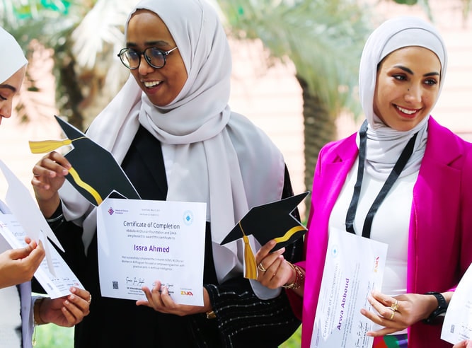 Graduates smiling as they hold up their ZAKA certificates of completion