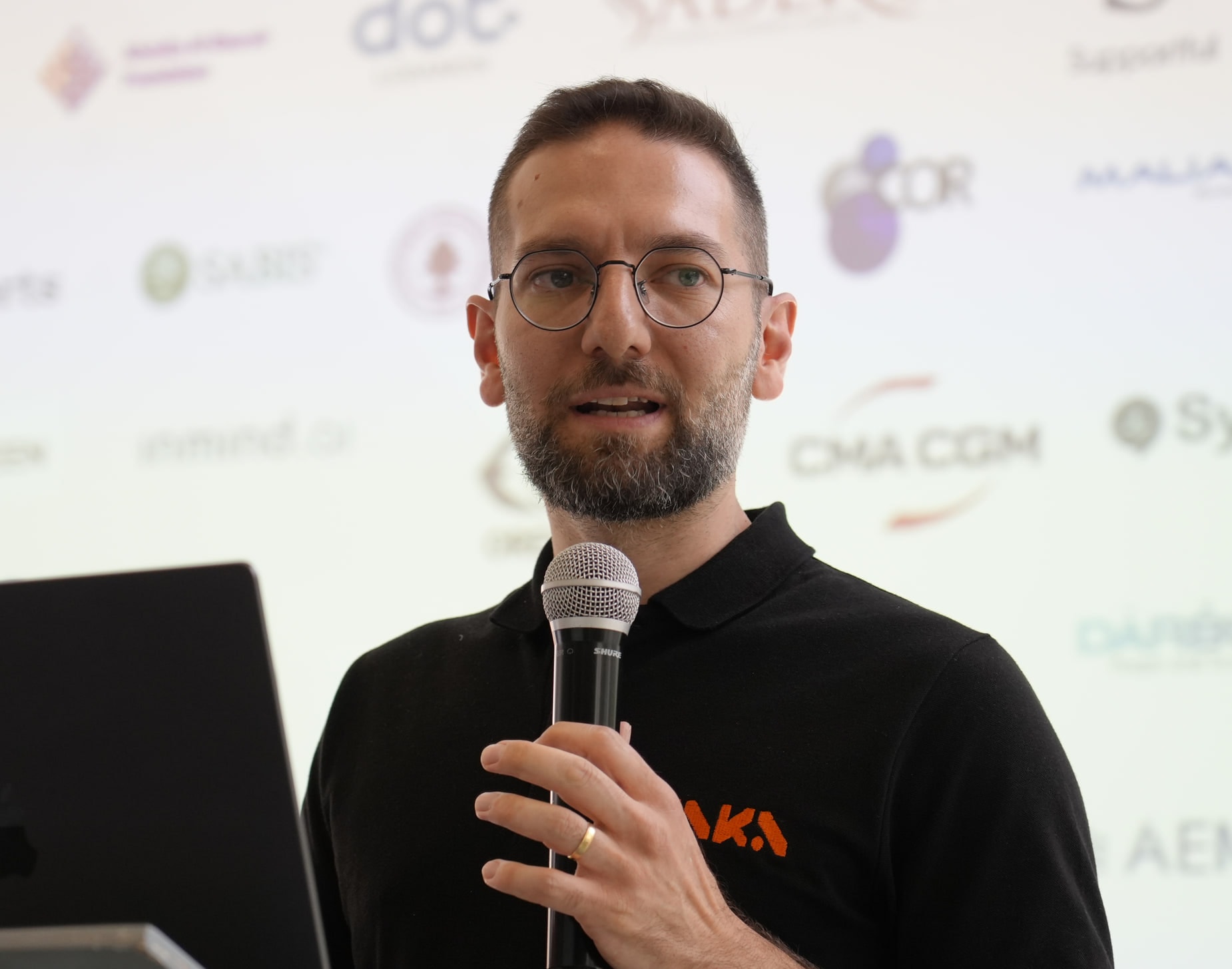 Christophe Zoghbi, CEO of ZAKA, speaking into a microphone on stage